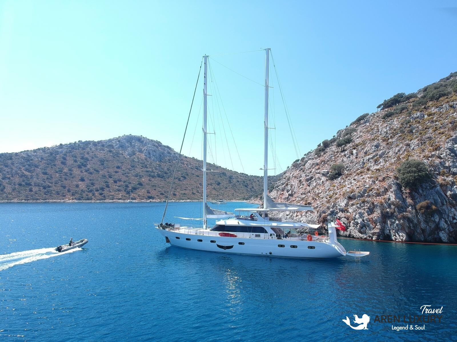 High-angle aerial view of the 35m Angelo 3 motorsailer yacht anchored in a deep blue Mediterranean bay.