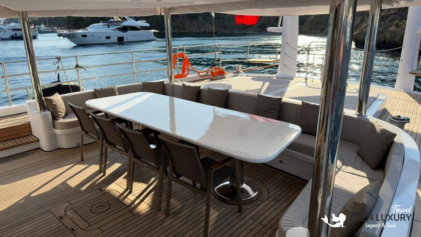 Side profile of the Angelo 3 motorsailer showing the sleek hull, flybridge, and dual masts against a coastal backdrop