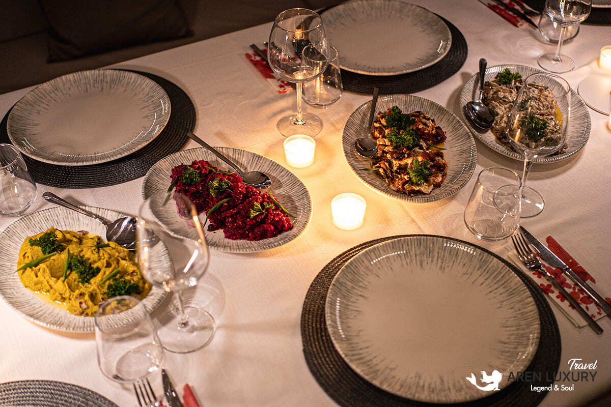 Side profile of the Angelo 3 motorsailer showing the sleek hull, flybridge, and dual masts against a coastal backdrop
