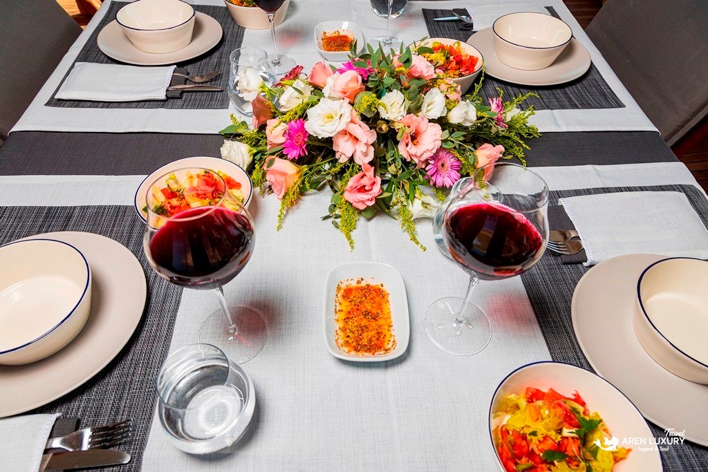 Gulet-Bodrum-Queen-Fine-Dining-Detail Close-up of a yacht dining table with red wine, appetizers, and a fresh floral centerpiece.