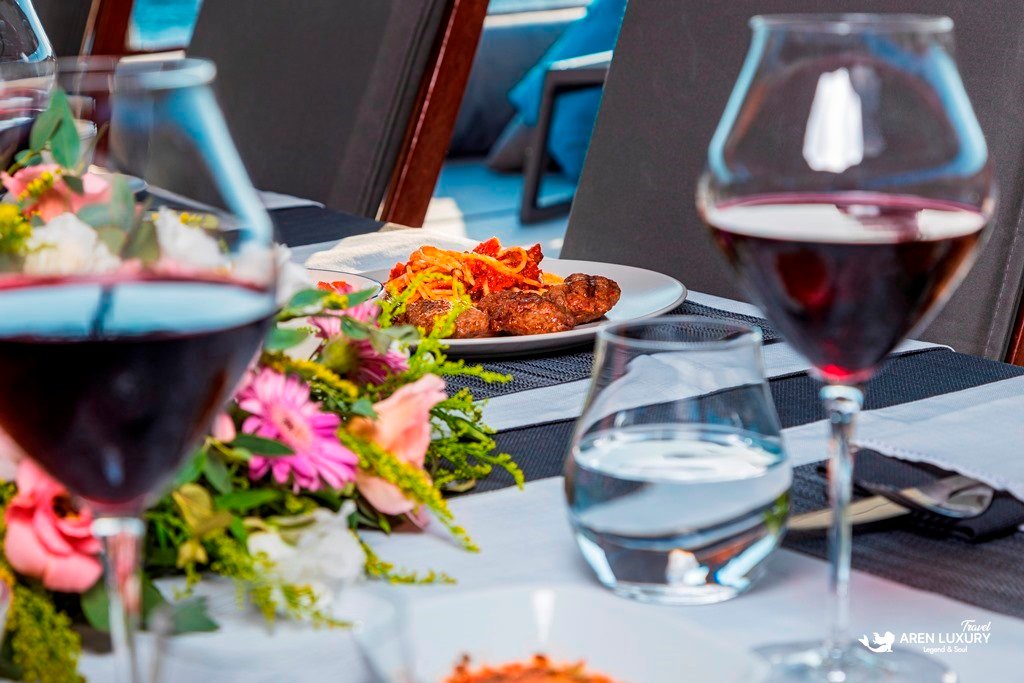 Gulet-Bodrum-Queen-Sunset-Dinner-Service Close-up shot of two red wine glasses on a decorated yacht dinner table at dusk.