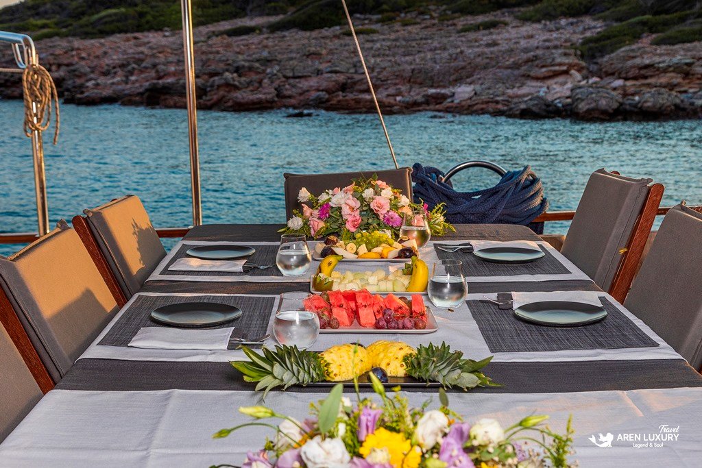 gulet-holiday-guide-sunset-dining-experience Fresh fruit platter and elegant table setting on a yacht deck at sunset.