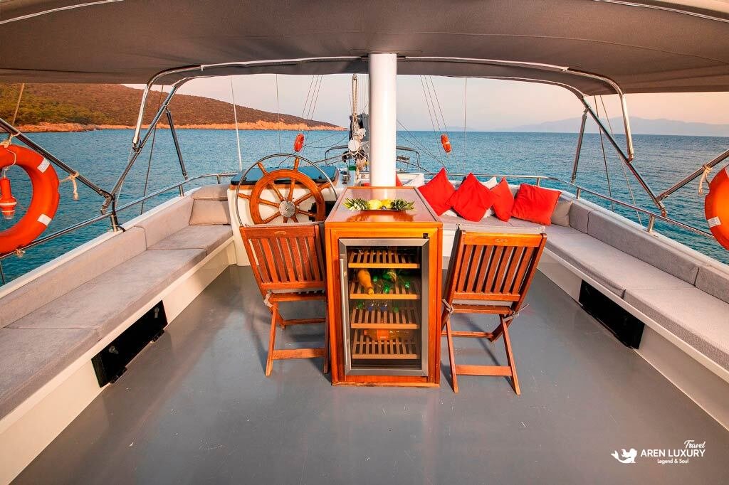 gulet-holiday-guide-aft-deck-helm Classic wooden steering wheel and comfortable aft lounge area on a luxury gulet.