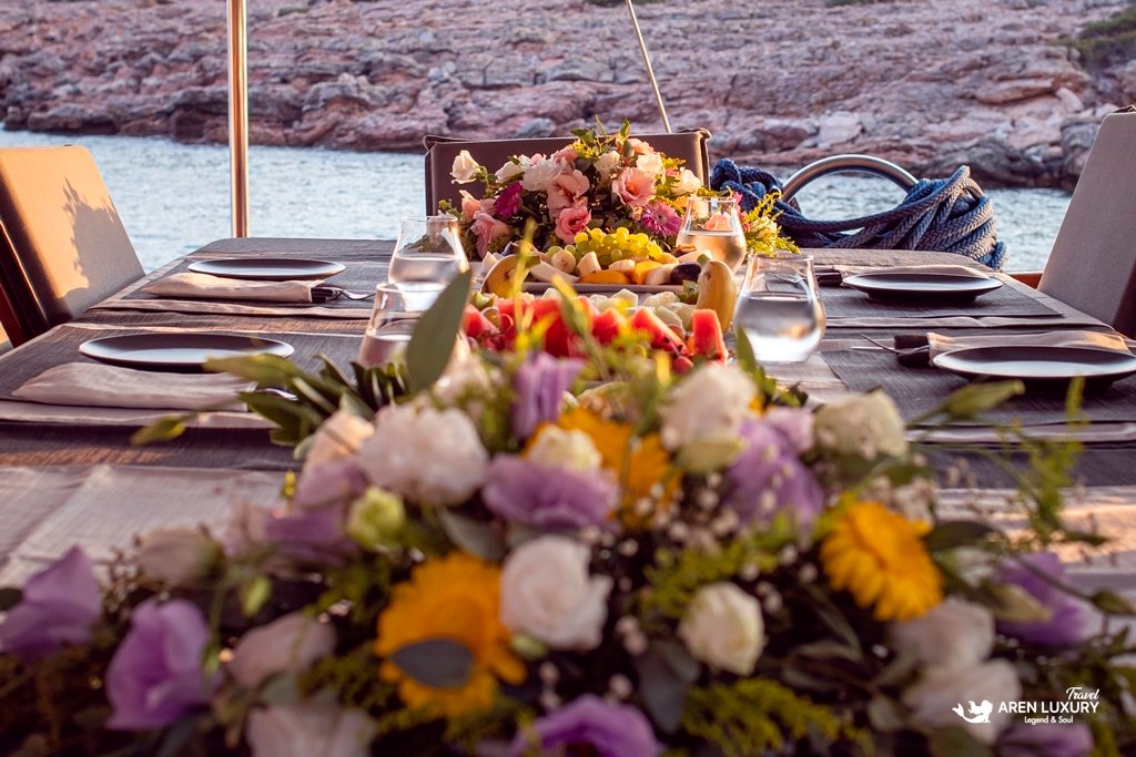 bodrum-queen-gulet-luxury-dinner-setting Beautifully decorated dining table with fresh flowers on the Bodrum Queen Gulet at sunset.