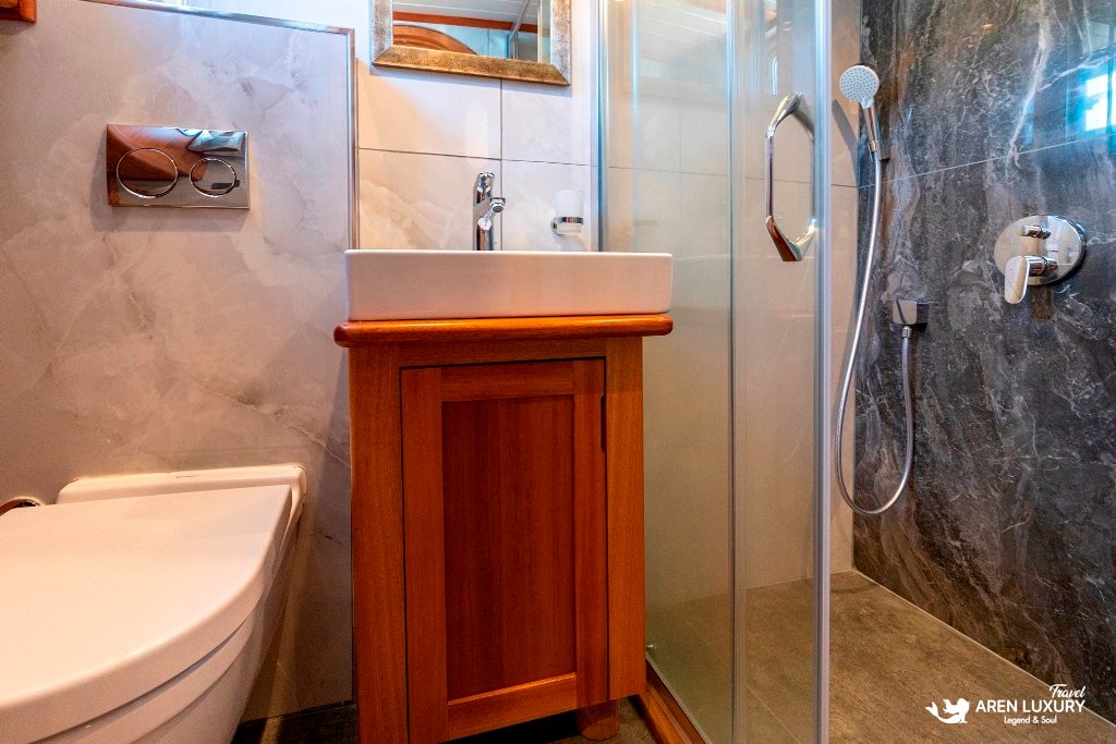 bodrum-queen-gulet-luxury-ensuite-amenities Modern ensuite bathroom with wooden vanity and high-end stone tiling on the Bodrum Queen Gulet.