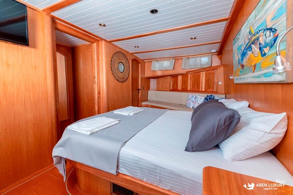 bodrum-queen-gulet-deluxe-master-cabin Deluxe master cabin on the Bodrum Queen Gulet featuring natural wood walls, nautical artwork, and a comfortable double bed.