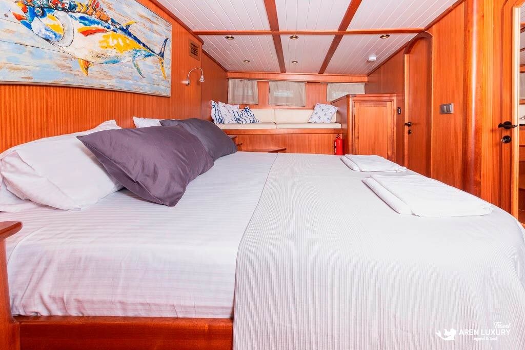 bodrum-queen-gulet-master-suite-interior Side view of the spacious master cabin on the Bodrum Queen Gulet with a large double bed and nautical wall art.