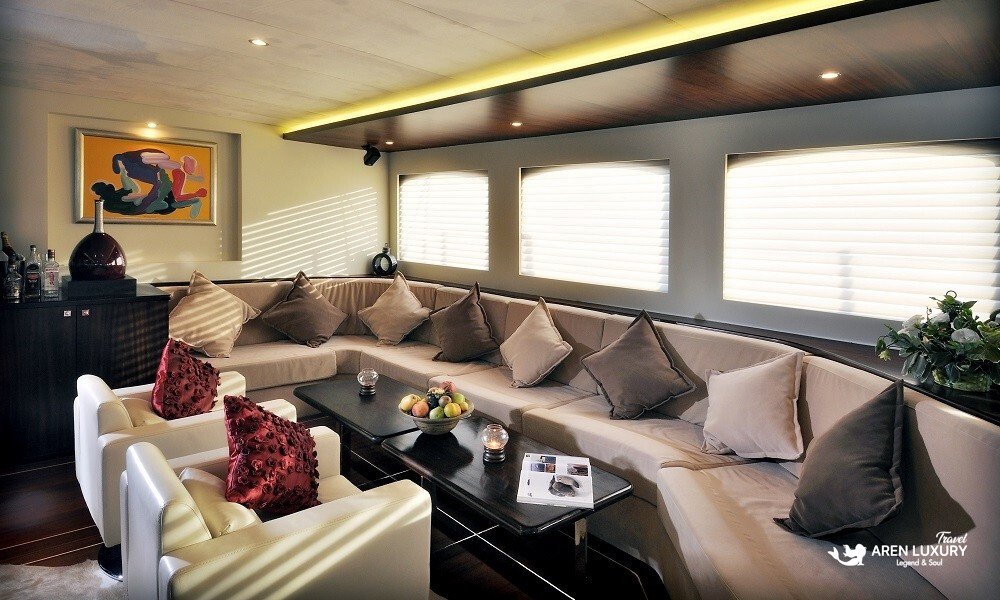 Casa-Dell-Arte-2-Gulet-Bodrum-Luxury-Lounge Luxurious indoor lounge area of Casa Dell'Arte 2 gulet in Bodrum featuring plush seating, modern art, and elegant wooden finishes.