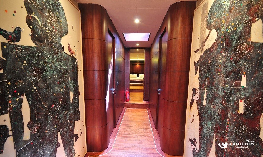 Casa-Dell-Arte-2-Gulet-Art-Gallery-Corridor Elegant hallway on Casa Dell'Arte 2 luxury gulet, featuring large-scale contemporary abstract paintings, polished mahogany wood paneling, and warm recessed lighting.