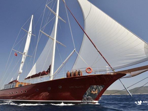 Full view of the Casa Dell'Arte 2 luxury gulet sailing in the Aegean Sea, showcasing its classic wooden hull and white sails under a clear blue sky.