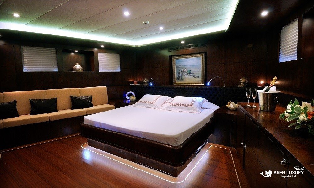 Casa-Dell-Arte-2-Gulet-Master-Cabin-Luxury Luxury master cabin interior of Casa Dell'Arte 2 gulet in Bodrum, featuring a queen-sized bed, ambient lighting, and elegant dark wood finish.