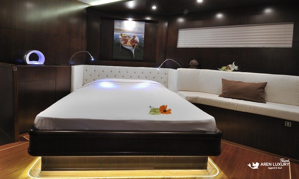 Casa-Dell-Arte-2-Gulet-Double-Guest-Cabin-Luxury Luxurious double guest cabin on the Casa Dell'Arte 2 gulet, featuring a queen-sized bed with ambient LED under-lighting, modern art, and dark wood paneling.