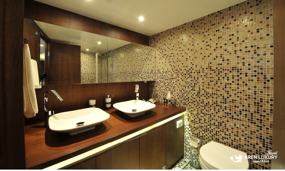 Casa-Dell-Arte-2-Gulet-Ensuite-Bathroom-Luxury Contemporary ensuite bathroom on Casa Dell'Arte 2 luxury gulet, featuring mosaic tile walls, a sleek white vessel sink, and premium dark wood finishes.