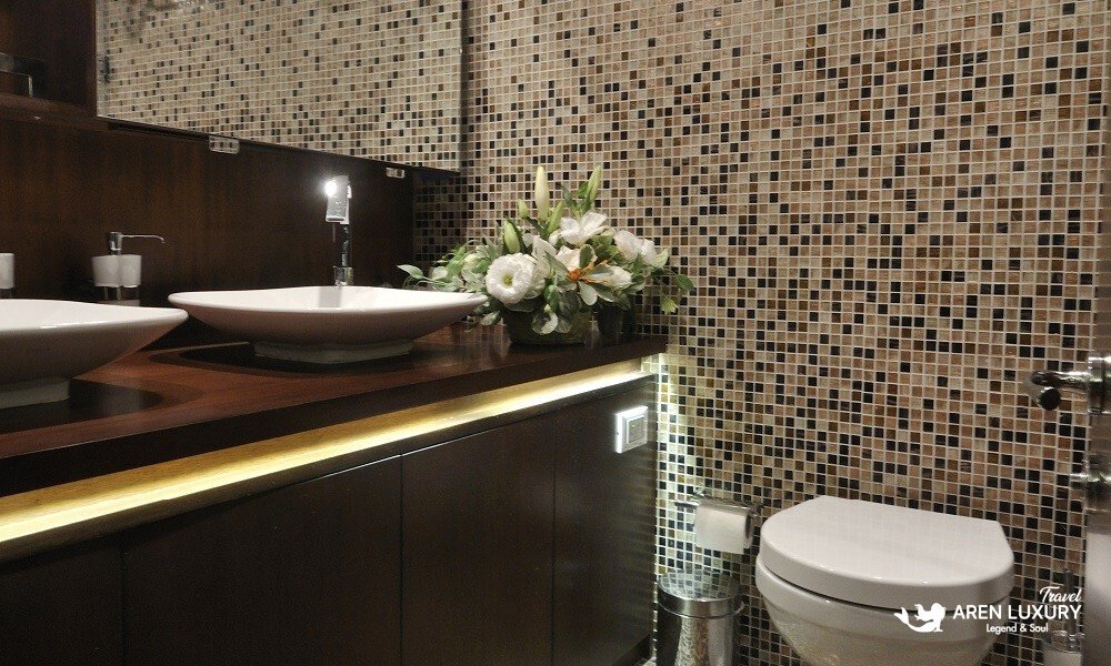 Casa-Dell-Arte-2-Gulet-Luxury-Ensuite-Bathroom Modern ensuite bathroom on the Casa Dell'Arte 2 luxury gulet, featuring mosaic tile walls, a sleek vessel sink, dark wood cabinetry, and ambient LED lighting.