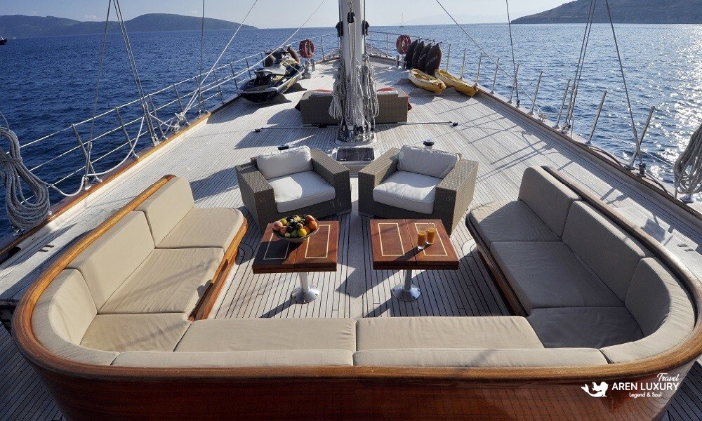 Casa-Dell-Arte-2-Luxury-Gulet-Forward-Deck Expansive forward deck of Casa Dell'Arte 2 luxury gulet featuring large built-in sofas, sun loungers, and water sports equipment like jet skis and kayaks.