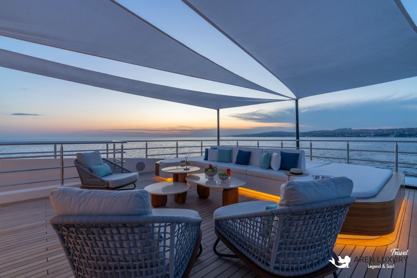 Elegant sundeck lounge on the Eternal Spark yacht at sunset featuring plush blue and white seating under a modern sunshade.