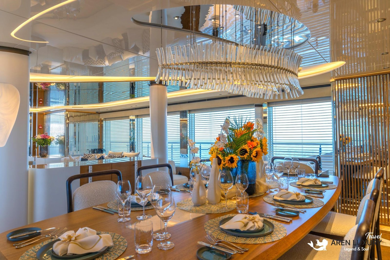 Luxurious interior dining salon of Eternal Spark yacht featuring a crystal chandelier, floral centerpieces, and a large wooden table set for a formal dinner.