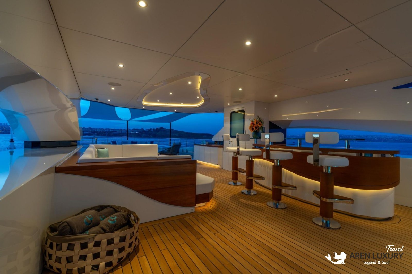 Sophisticated sundeck bar on the Eternal Spark yacht at night featuring glowing warm LED lighting, modern bar stools, and a comfortable lounge area.