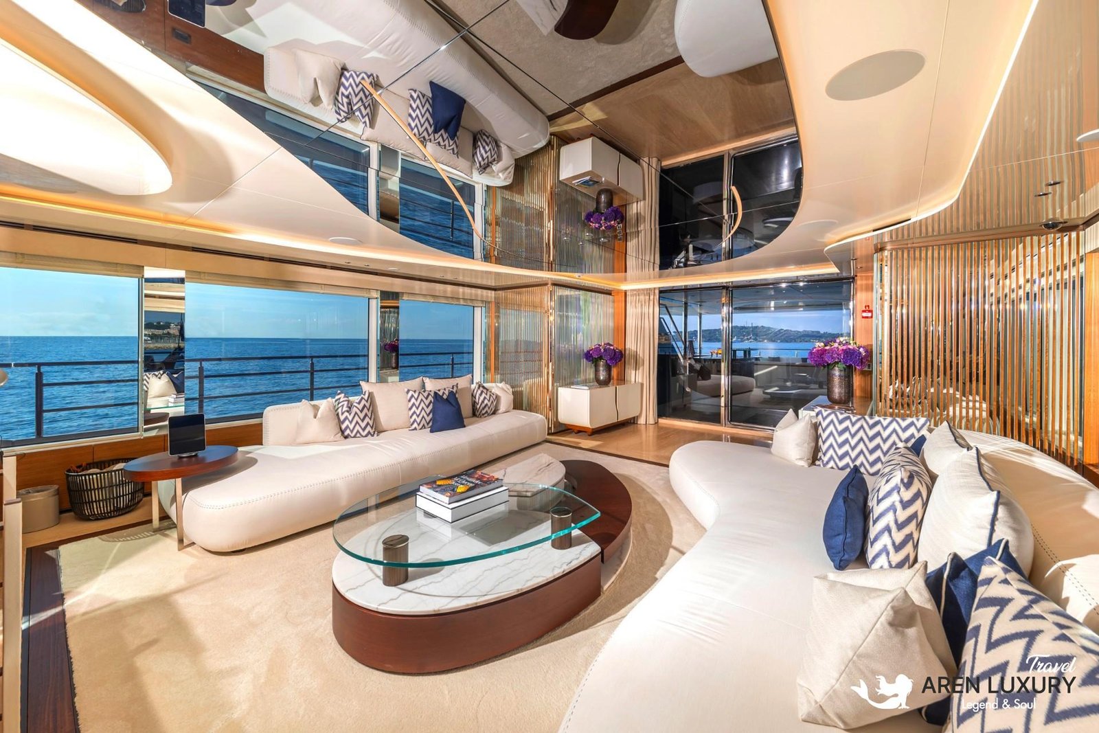 Ultra-modern main salon of Eternal Spark yacht featuring curved white leather sofas, a marble coffee table, and a reflective mirrored ceiling.