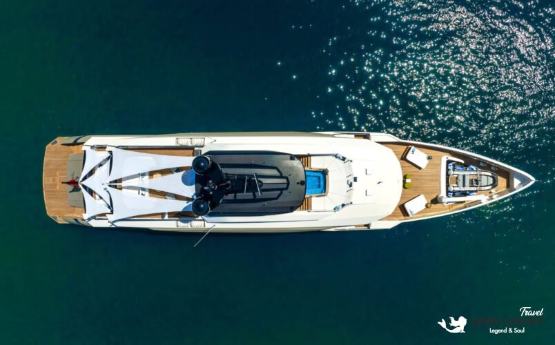 Full side profile of the luxury charter yacht Eternal Spark cruising on calm blue water under a bright sky.