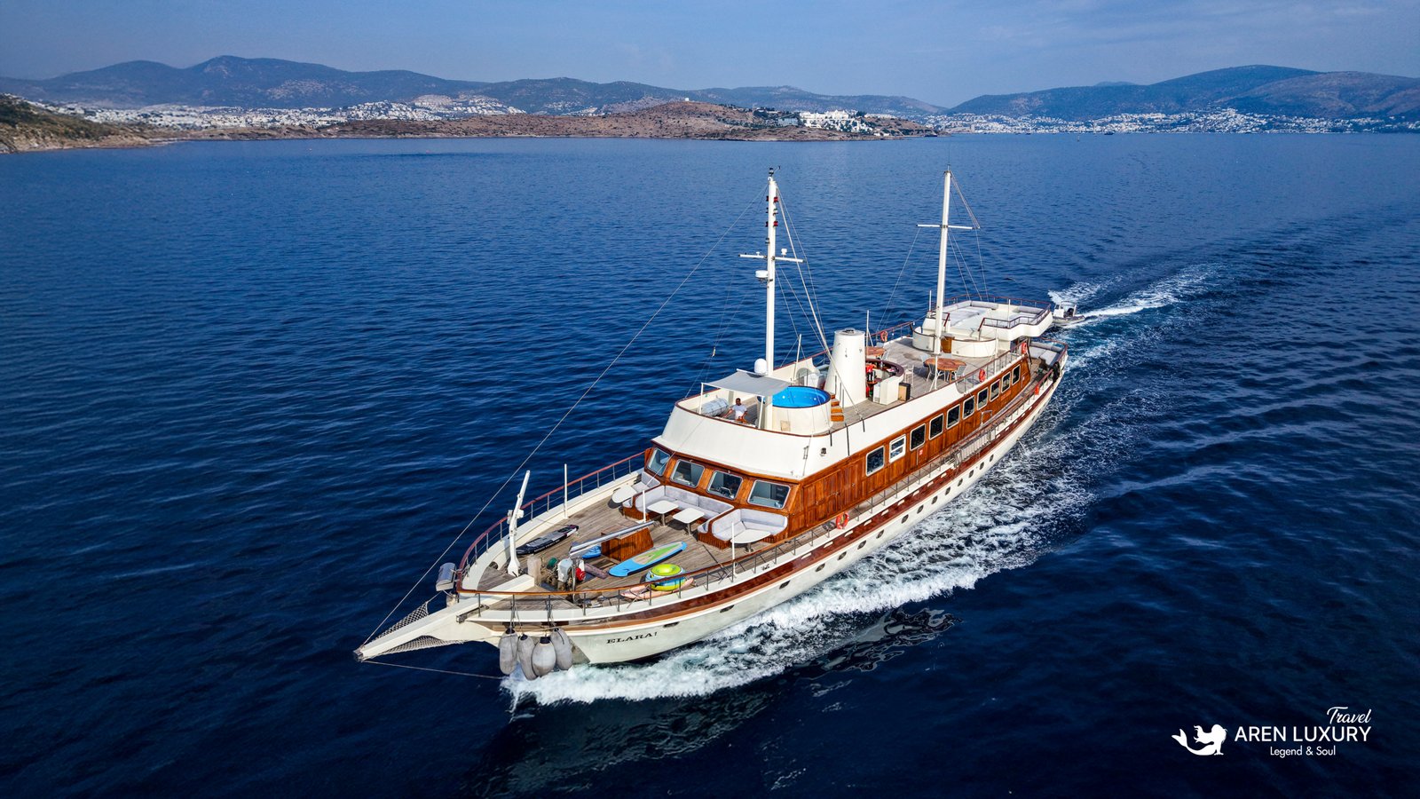 Aerial view of the Elara 1 luxury gulet yacht cruising on calm blue waters near the coast.