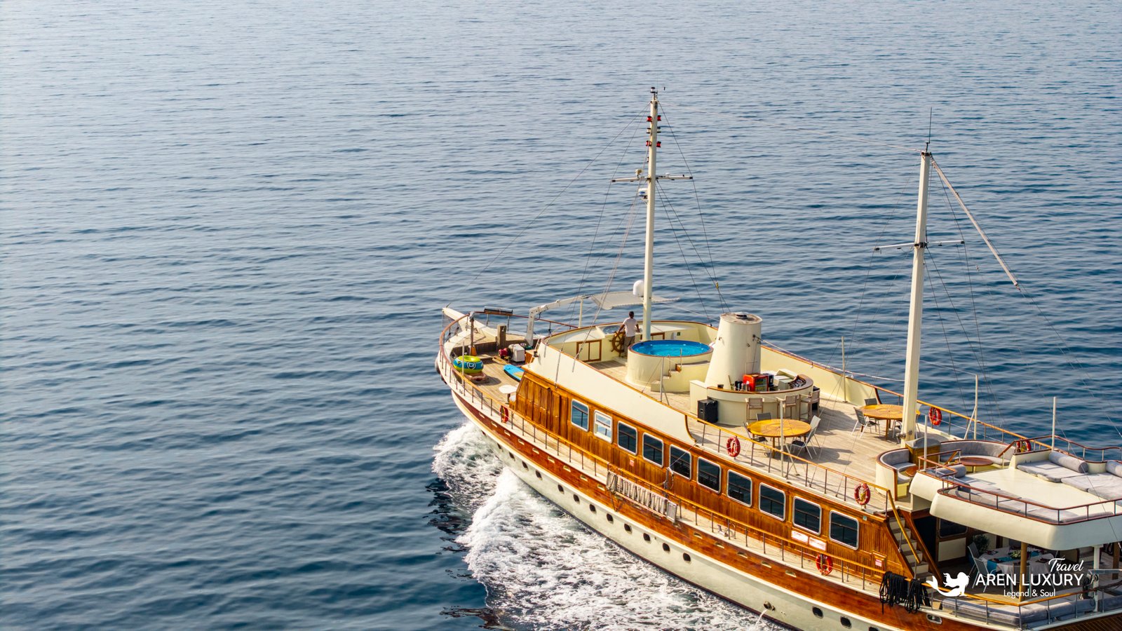 elara-1-gulet-deck-amenities Close-up aerial view of the Elara 1 gulet deck featuring a blue jacuzzi and outdoor dining tables.