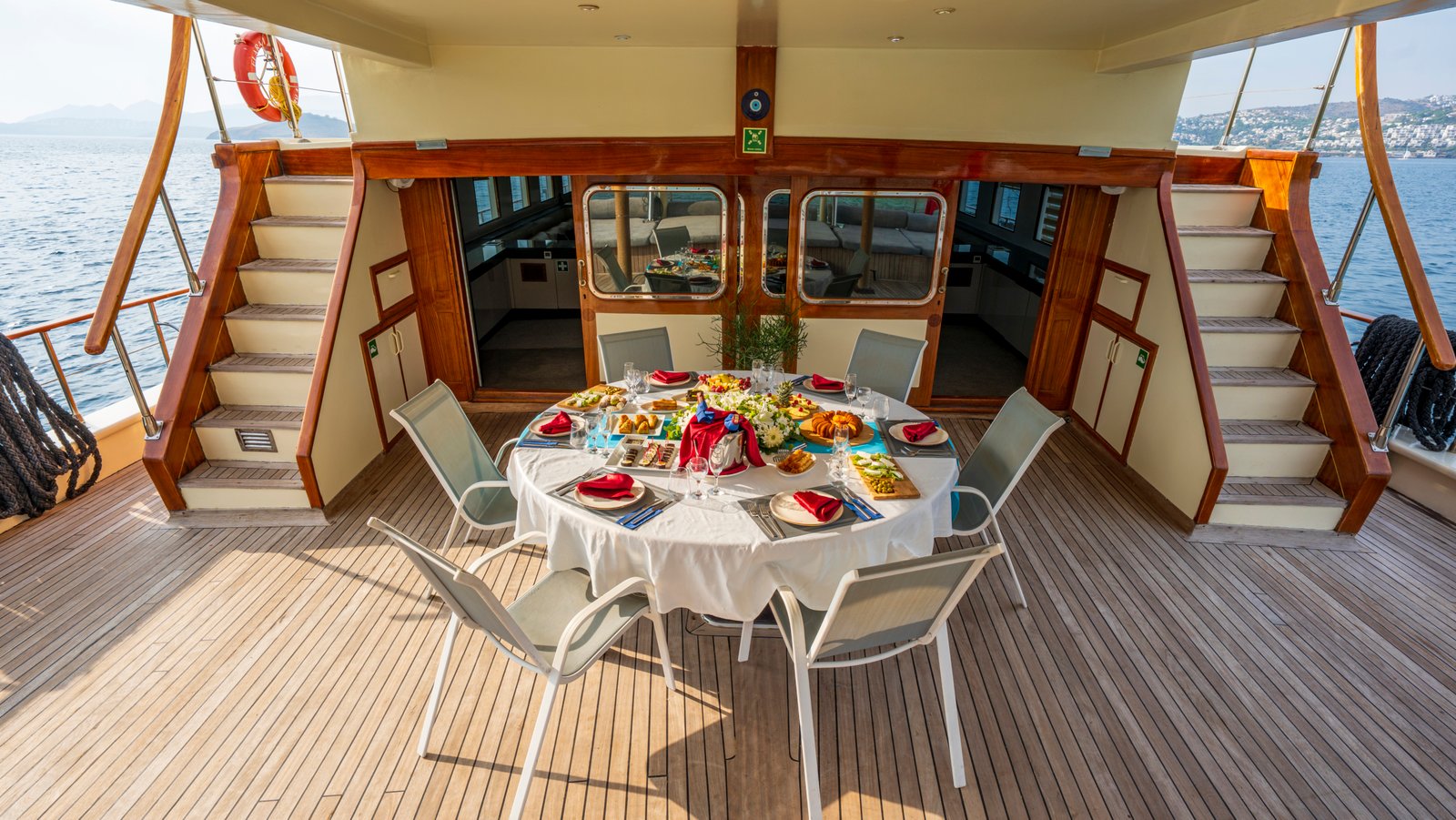 elara-1-gulet-aft-deck-dining-setup Rear deck of Elara 1 gulet featuring an elegantly set round dining table for an alfresco Mediterranean meal.