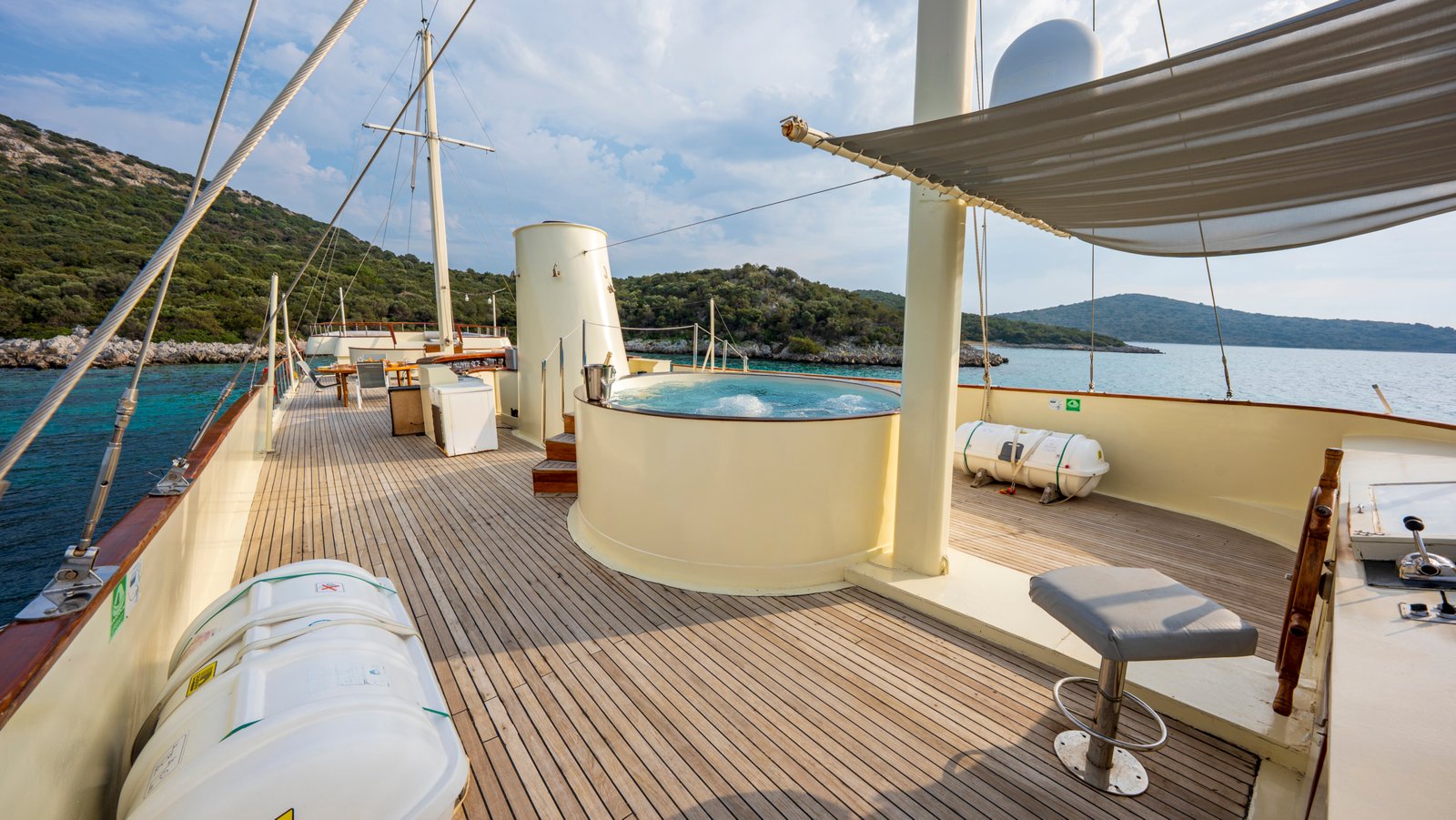 elara-1-gulet-luxury-dining-deck Close-up of a circular wooden dining table on the deck of the Elara 1 gulet, set with fresh fruit and appetizers overlooking the sea.