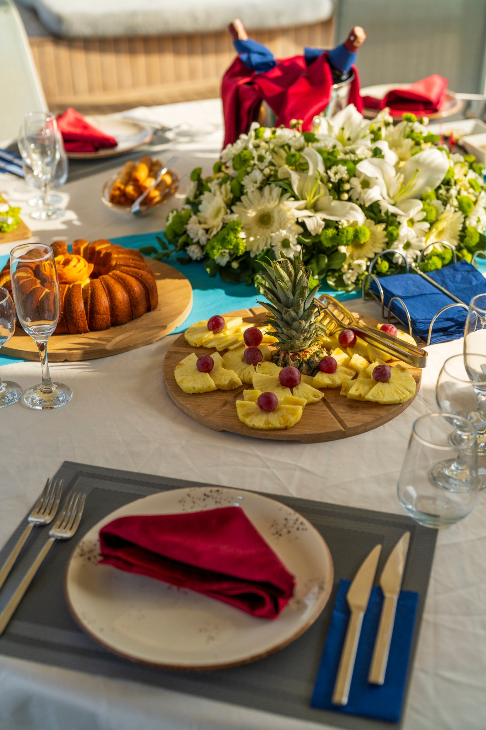 elara-1-gulet-dining-detail-vertical Close-up vertical shot of a beautifully set dining table on the Elara 1 gulet, featuring floral arrangements and fresh desserts.