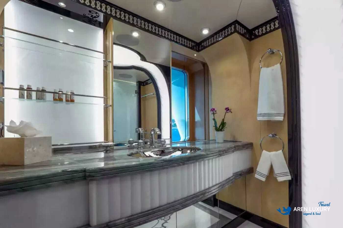 View of the luxurious owner's stateroom on the 80m superyacht Elements, showcasing the etched-mirrored glass detailing and white leather furnishings.