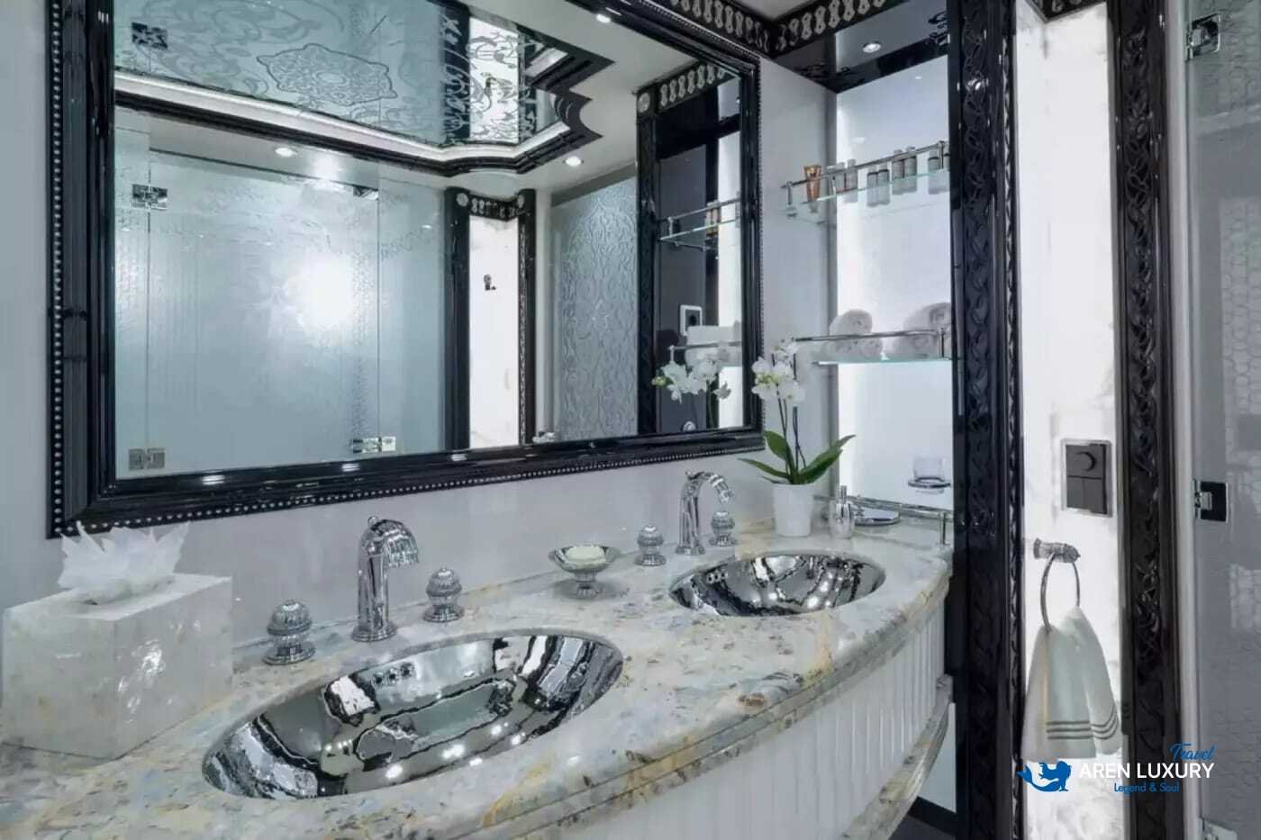 View of the luxurious owner's stateroom on the 80m superyacht Elements, showcasing the etched-mirrored glass detailing and white leather furnishings.