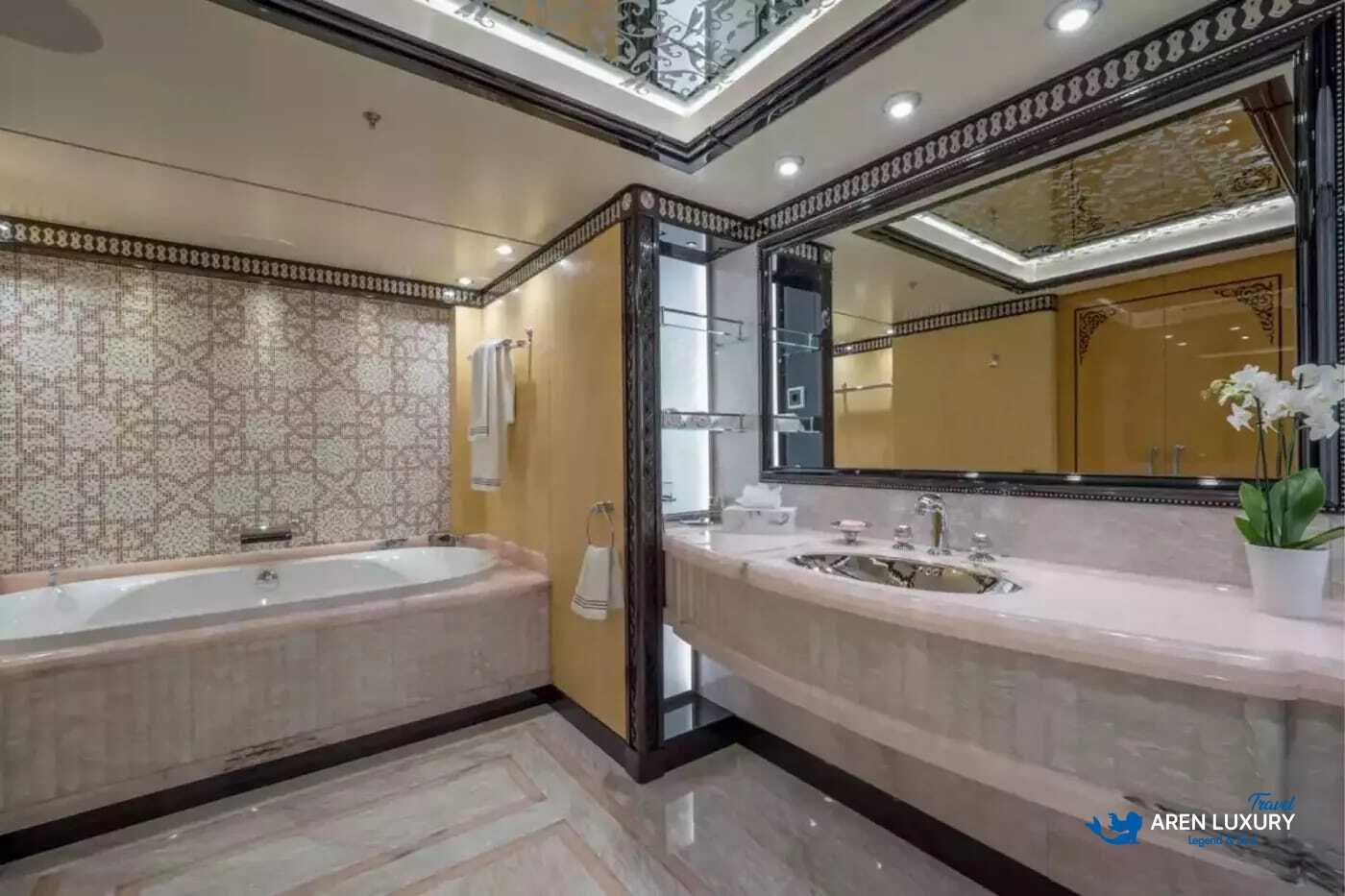 View of the luxurious owner's stateroom on the 80m superyacht Elements, showcasing the etched-mirrored glass detailing and white leather furnishings.