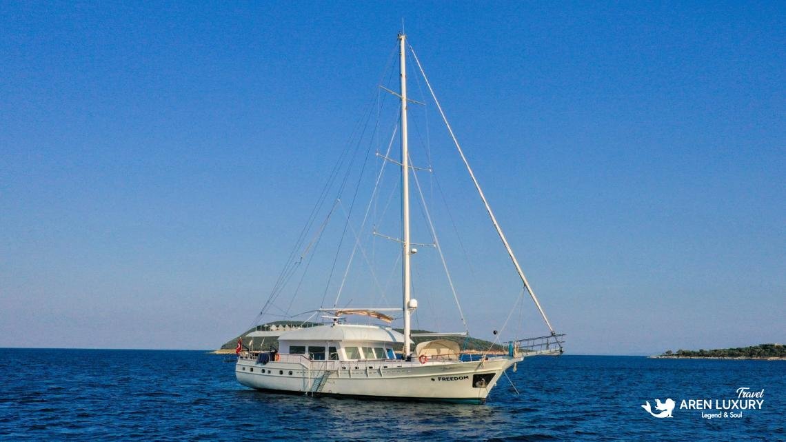 gulet-freedom-aerial-deck-jacuzzi-luxury-charter-bodrum Aerial top-down view of 30m luxury gulet Freedom cruising at sea, featuring flybridge jacuzzi and expansive teak decks.