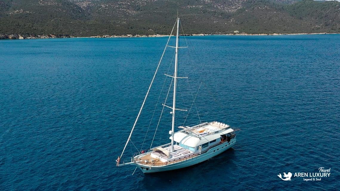 Side aerial view of luxury ketch Gulet Freedom cruising in turquoise waters with visible flybridge and sun decks.
