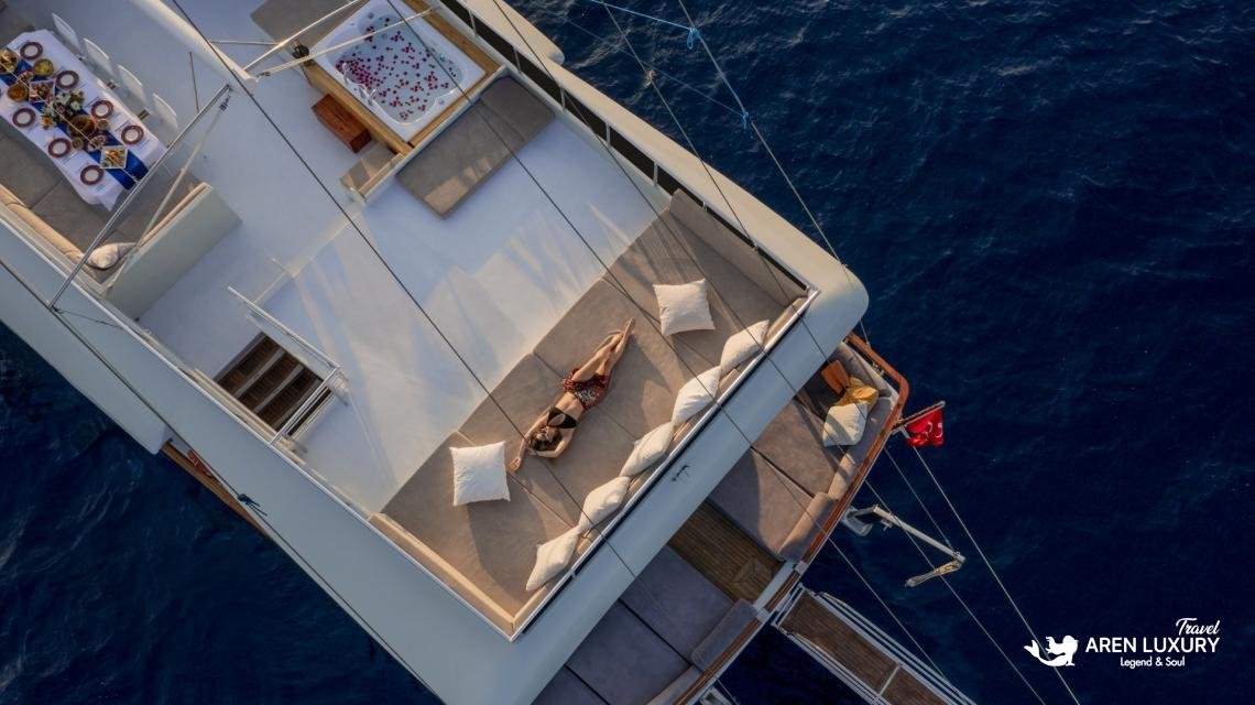 gulet-freedom-flybridge-jacuzzi-sunbathing Aerial view of a guest sunbathing on the expansive flybridge of Gulet Freedom next to the private jacuzzi.