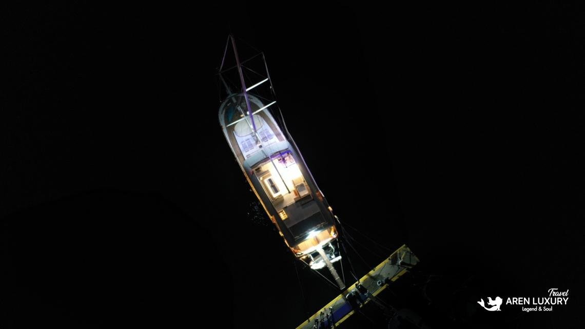gulet-freedom-night-aerial-illumination-luxury-charter Night aerial drone view of luxury gulet Freedom illuminated at sea with a glowing deck and underwater lights.