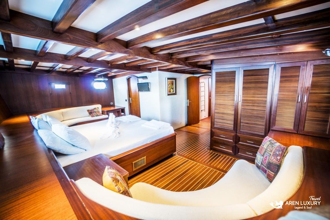 gulet-freedom-luxury-master-suite-interior-design Luxury master suite on Gulet Freedom featuring a large double bed, curved white sofa, and classic wooden yacht interior styling.