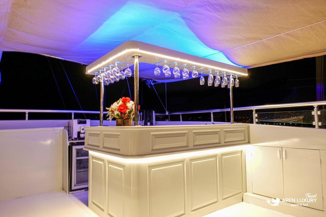 gulet-freedom-luxury-flybridge-bar-night-view Illuminated luxury wet bar on the flybridge of Gulet Freedom at night, featuring a white counter, hanging glassware, and soft blue accent lighting.