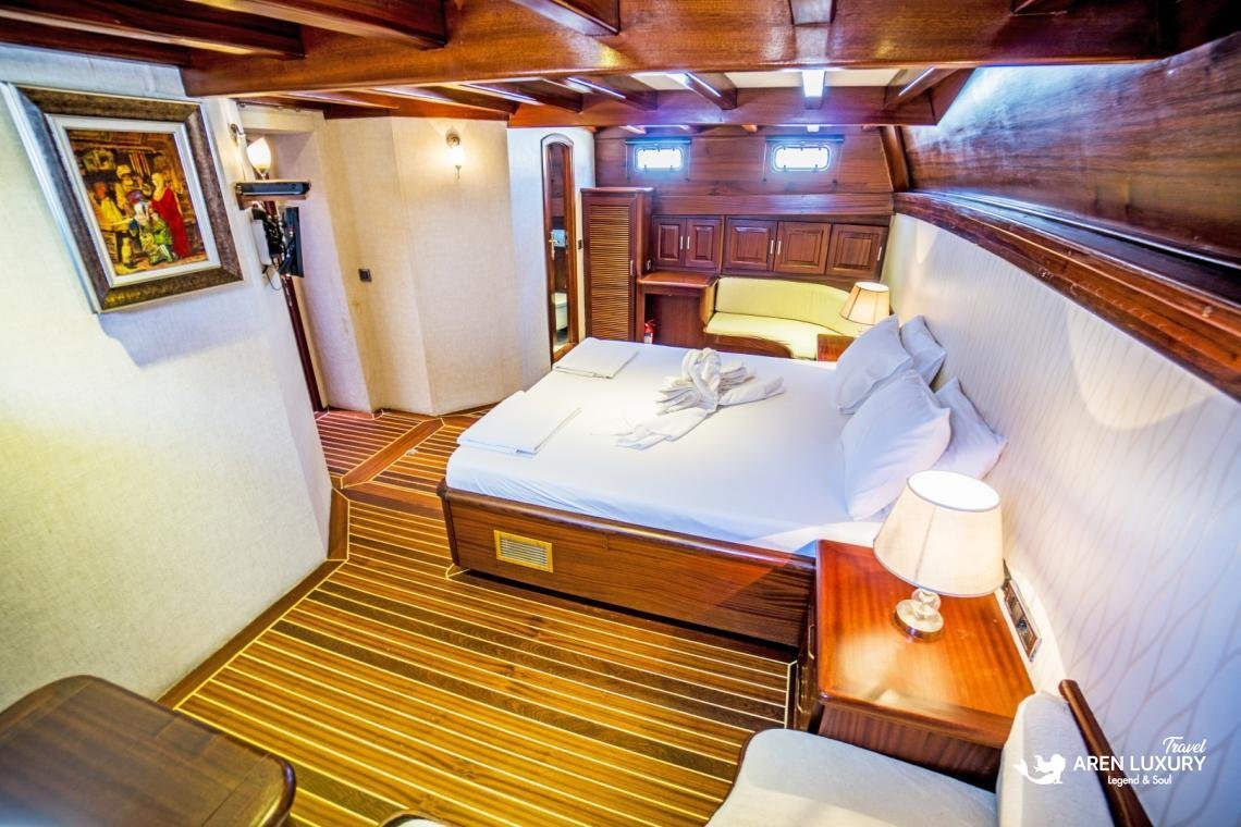 gulet-freedom-luxury-double-guest-cabin-interior Luxury double cabin on Gulet Freedom featuring a large bed, warm wood paneling, soft accent lighting, and a modern en-suite layout.