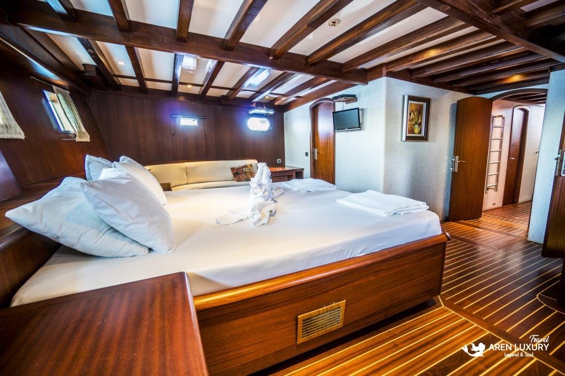 gulet-freedom-triple-cabin-family-accommodation Luxury triple cabin on Gulet Freedom featuring a large double bed, an integrated single bed, and warm wood finishes.