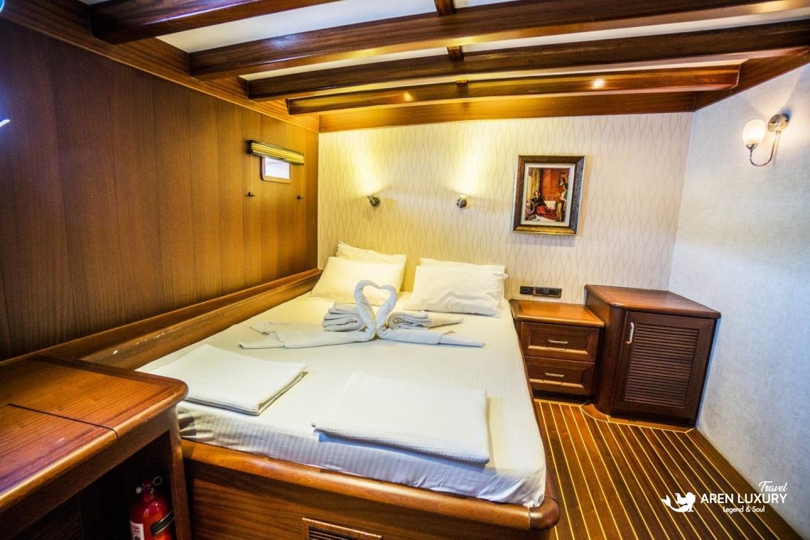 gulet-freedom-luxury-double-guest-cabin-interior Luxury double guest cabin on Gulet Freedom featuring a large bed, warm wood paneling, soft accent lighting, and a modern en-suite layout.