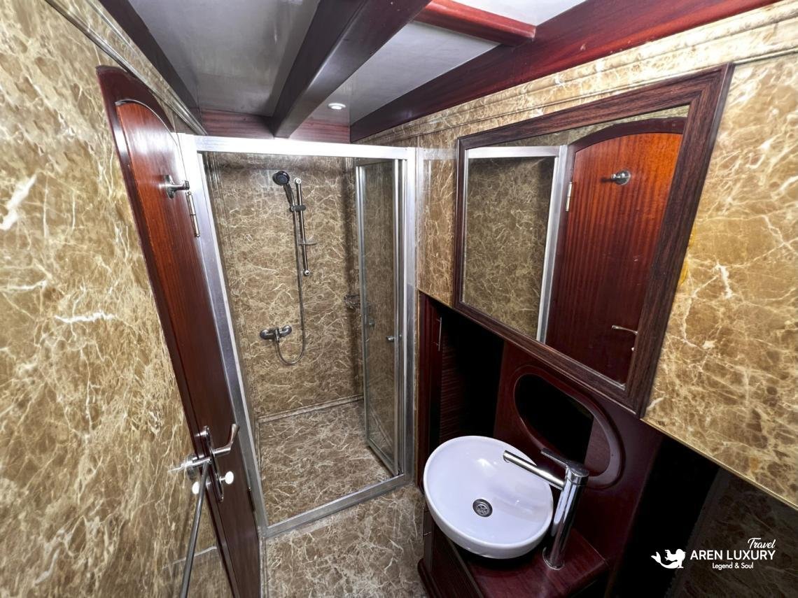 gulet-freedom-luxury-ensuite-bathroom-shower En-suite luxury bathroom on Gulet Freedom featuring a glass shower cabin, marble-patterned walls, and modern white porcelain fixtures.