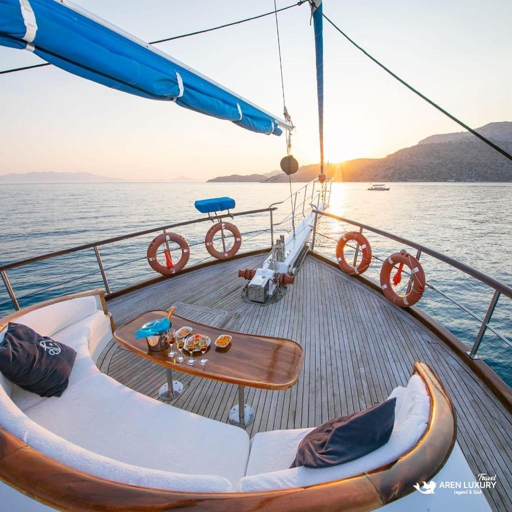 Luxury aft deck lounge on Gulet Gokce with sunset views over the Mediterranean, featuring plush cushions and cocktails.