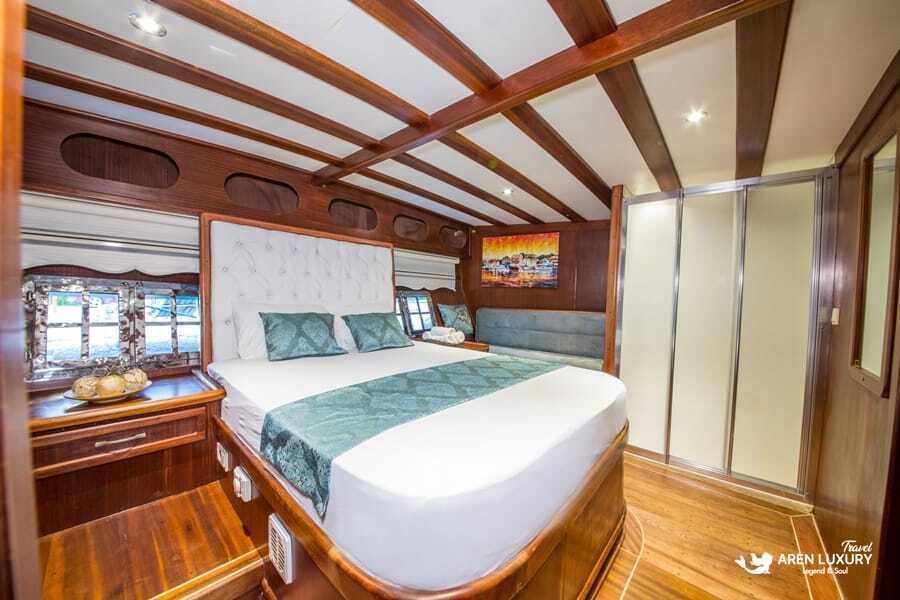 Modern double guest cabin on Gulet Gokce featuring white quilted headboards, mahogany wood paneling, and a large wardrobe.