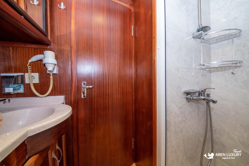 Private en-suite bathroom in a luxury cabin on Gulet Gokce, featuring a modern shower, marble-effect tiling, and mahogany wood finish.