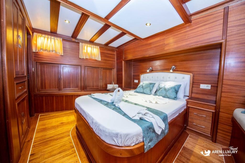Spacious boutique-style yacht cabin on Gulet Gokce featuring a white quilted double bed, warm recessed lighting, and integrated storage.