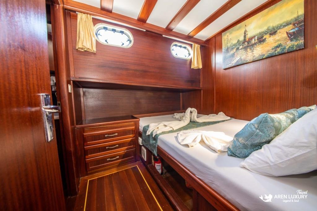 Luxury master cabin on Gulet Gokce featuring a large double bed, mahogany paneling, and an en-suite bathroom.