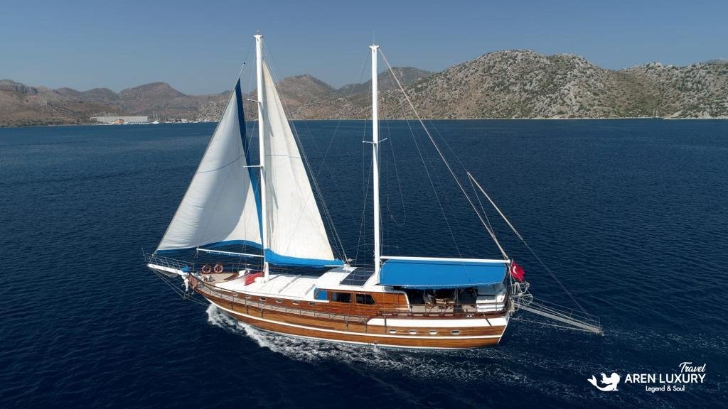 Traditional Turkish Gulet Gokce sailing under full white canvas in the turquoise waters of the Mediterranean.