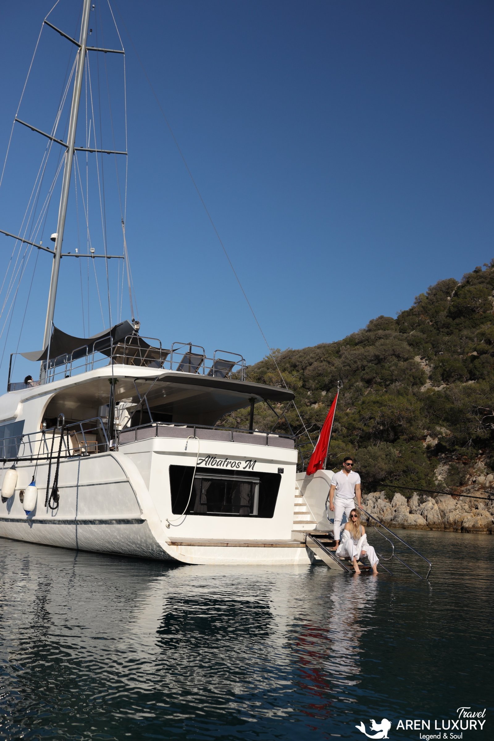 Gulet Charter Albatros M Exterior and Swimming Platform Rear view of Gulet Albatros M anchored in a turquoise bay with guests on the swimming platform.