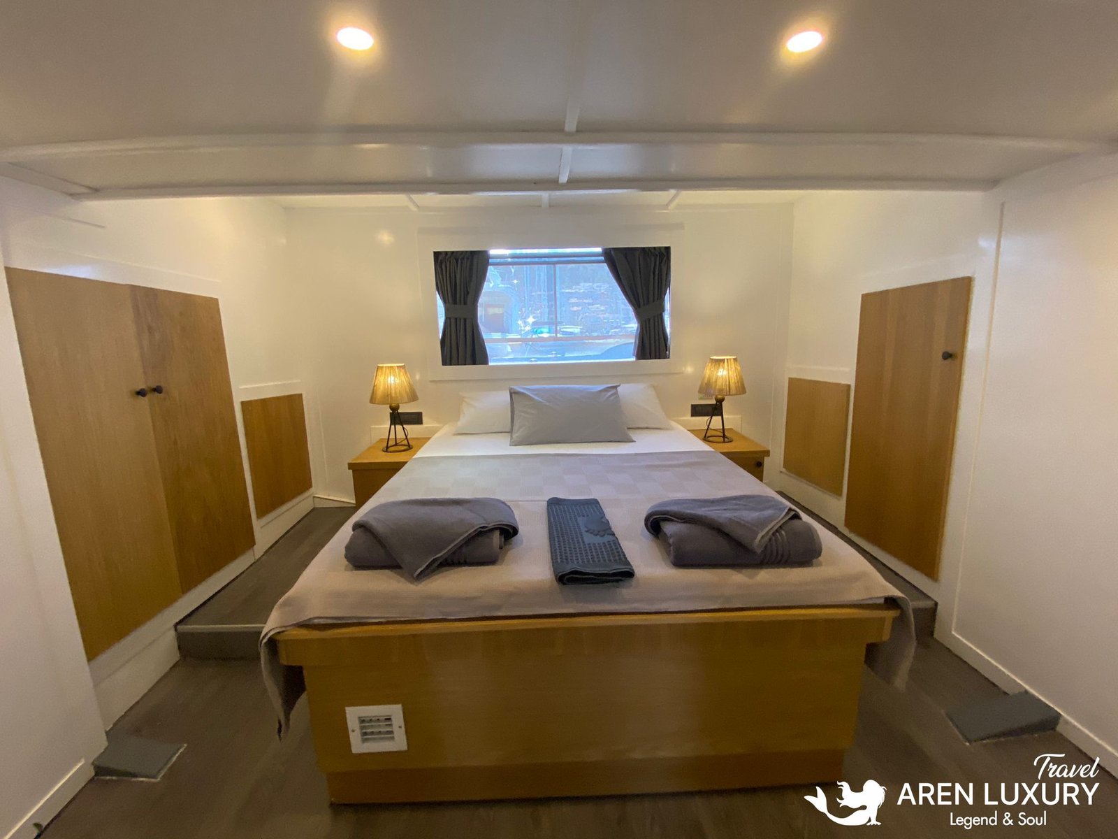 Gulet Albatros M Luxury Master Suite Spacious master cabin of Gulet Albatros M featuring a large double bed, symmetric wooden wardrobes, and elegant bedside lighting.